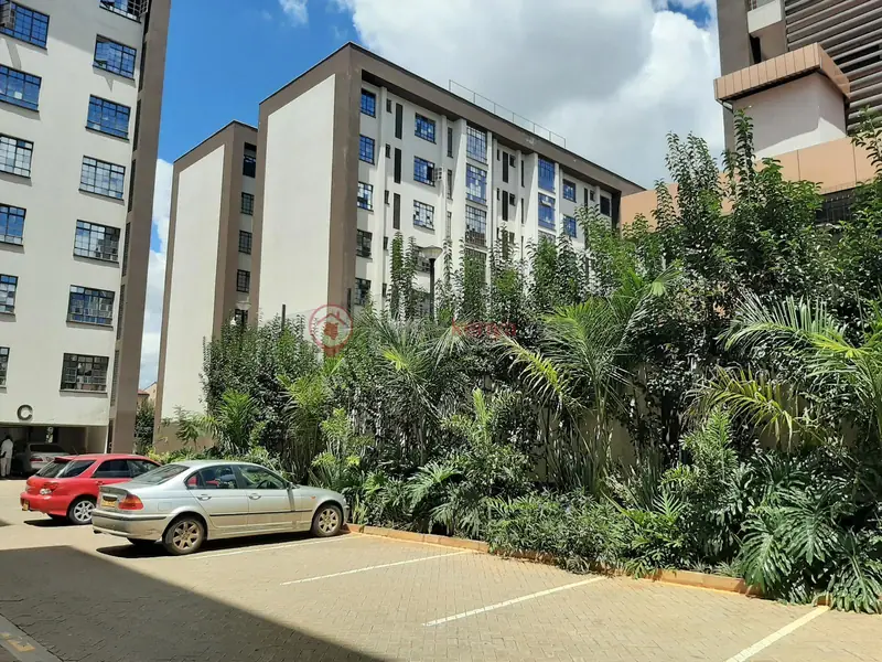 Lush tropical planting beside apartment blocks and parking, Freedom Heights