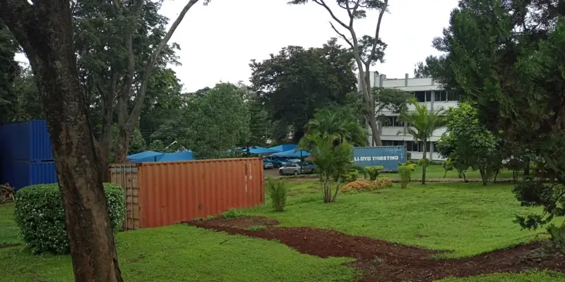 Before: NIA headquarters grounds before landscaping: rough grass, bare soil and a shipping container