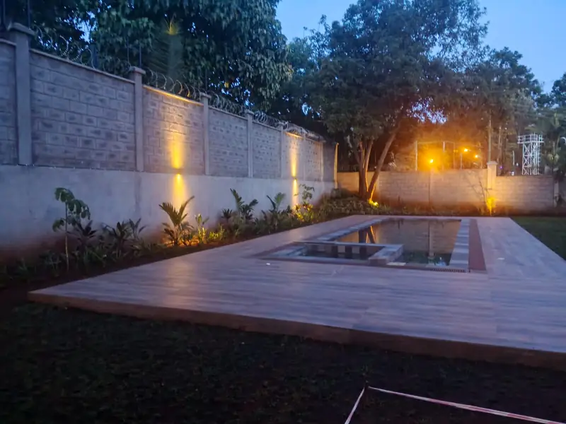 Timber deck and lit planting along a boundary wall at dusk, Roslyn residence